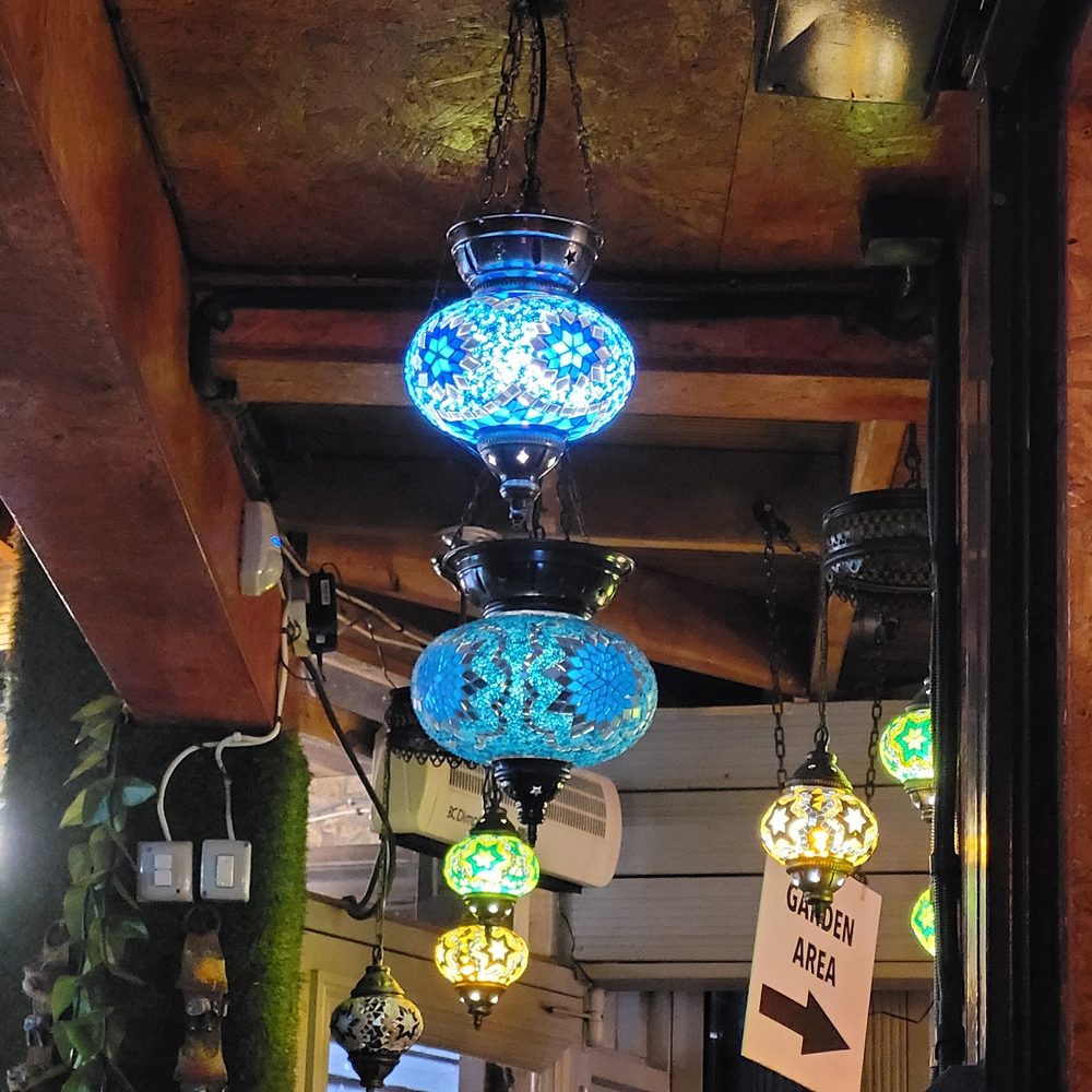 Coloured Turkish mosaic lanterns strung along the timber ceiling above the garden seating