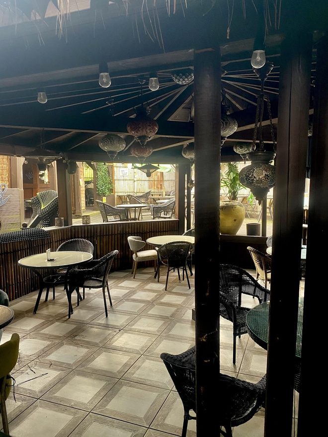 The empty covered garden dining area with bistro tables and festoon lights