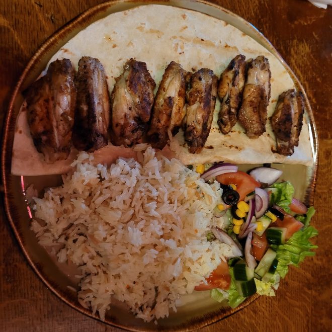 Platter of grilled chicken wings with rice and salad