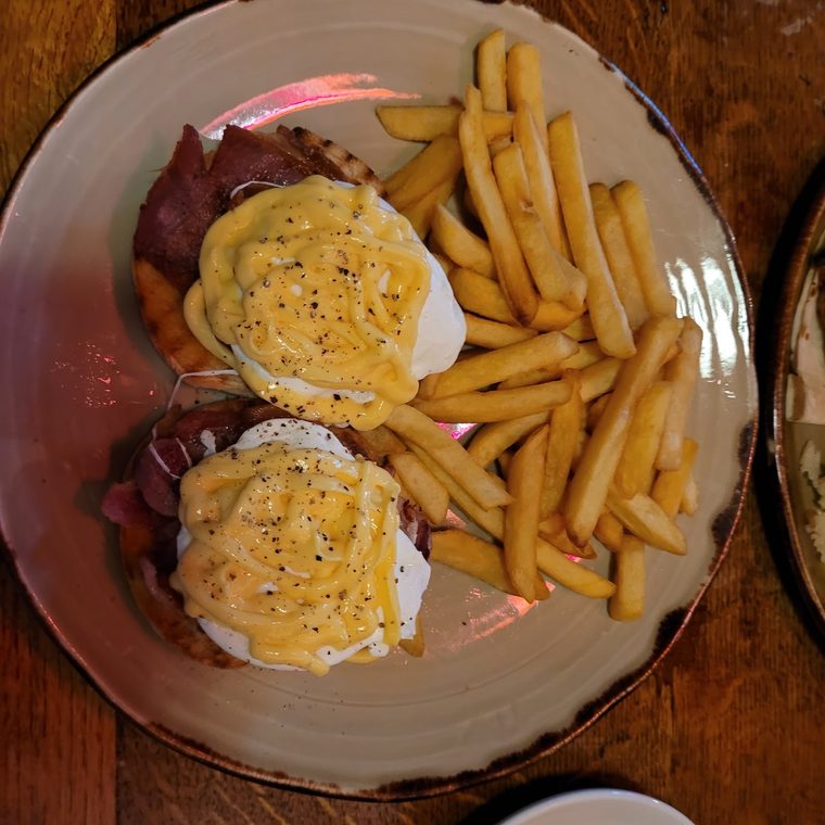 Eggs Benedict with bacon and a pile of chips