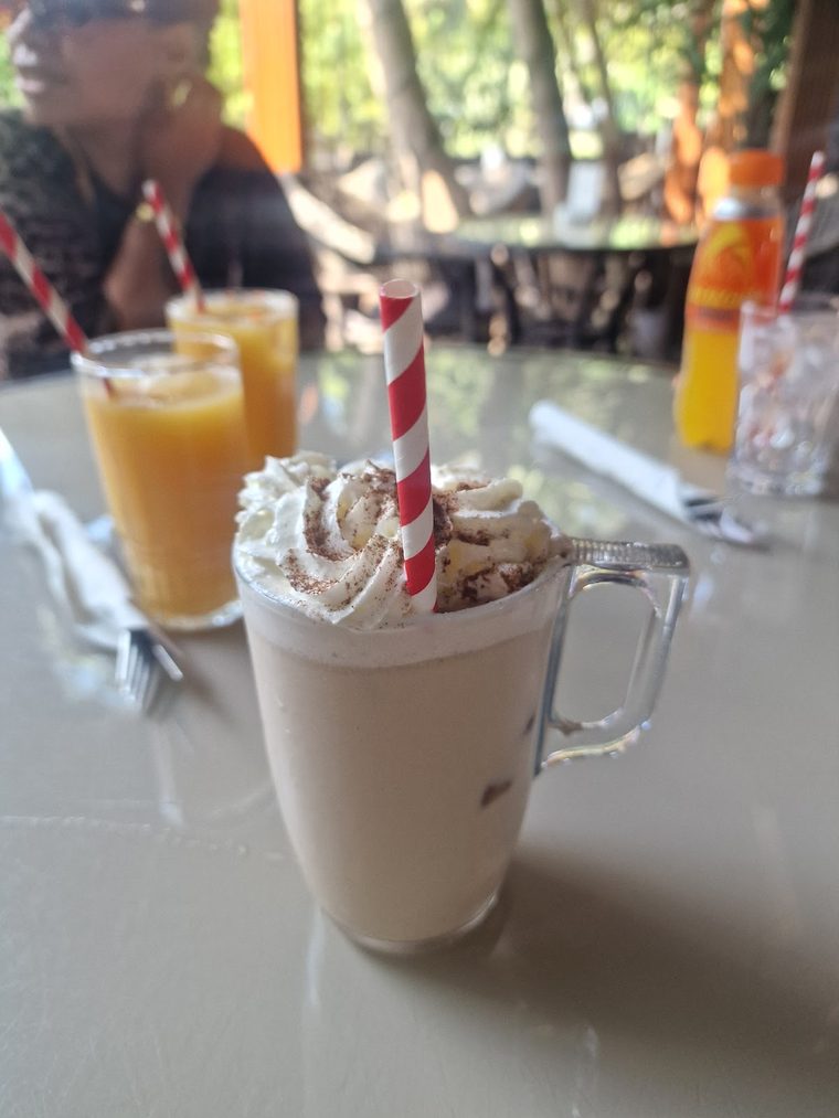 Hot chocolate topped with whipped cream, served in a tall glass mug